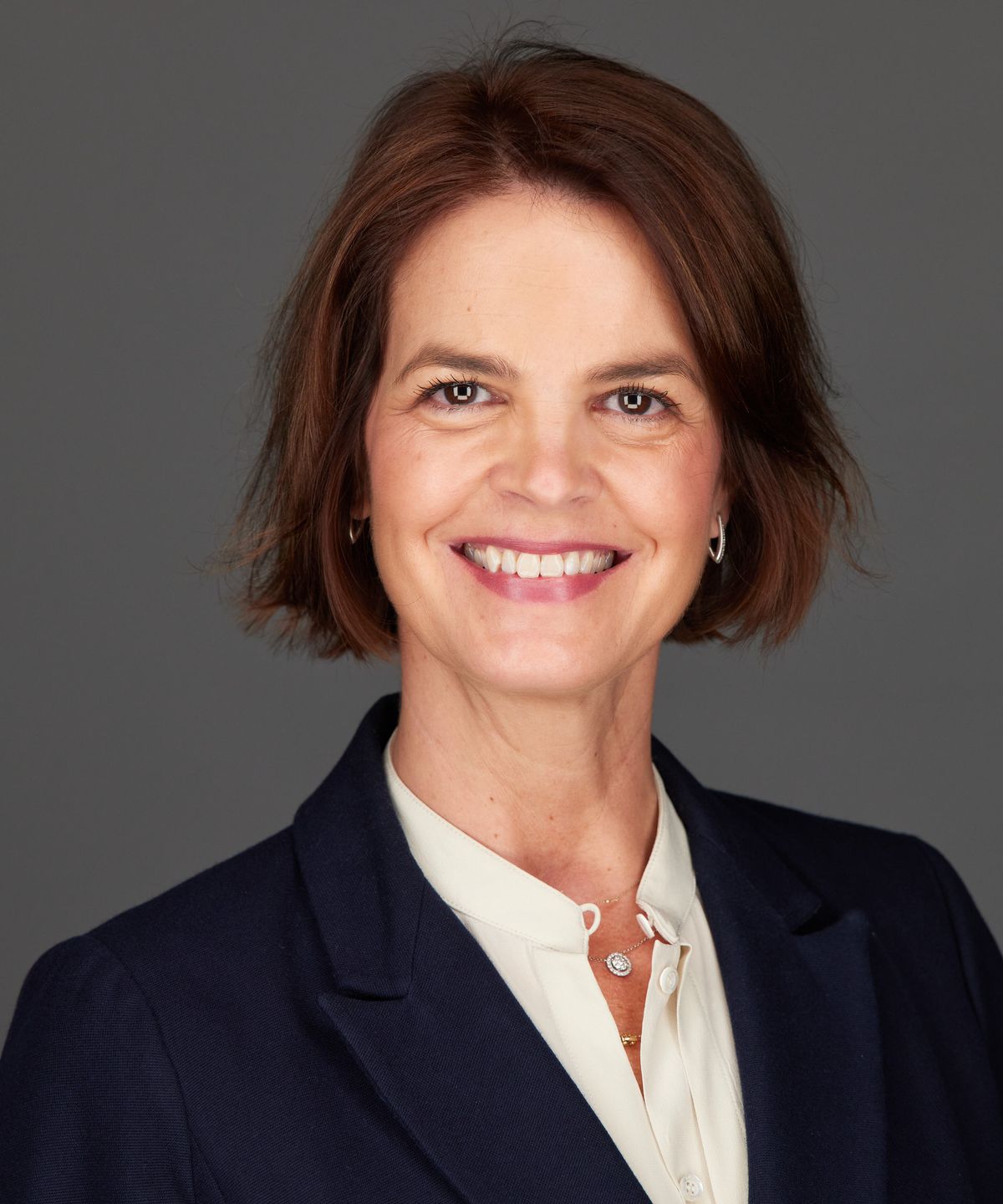 Picture of Lorena. A lady with brown polka hair and dark blue suit jacket